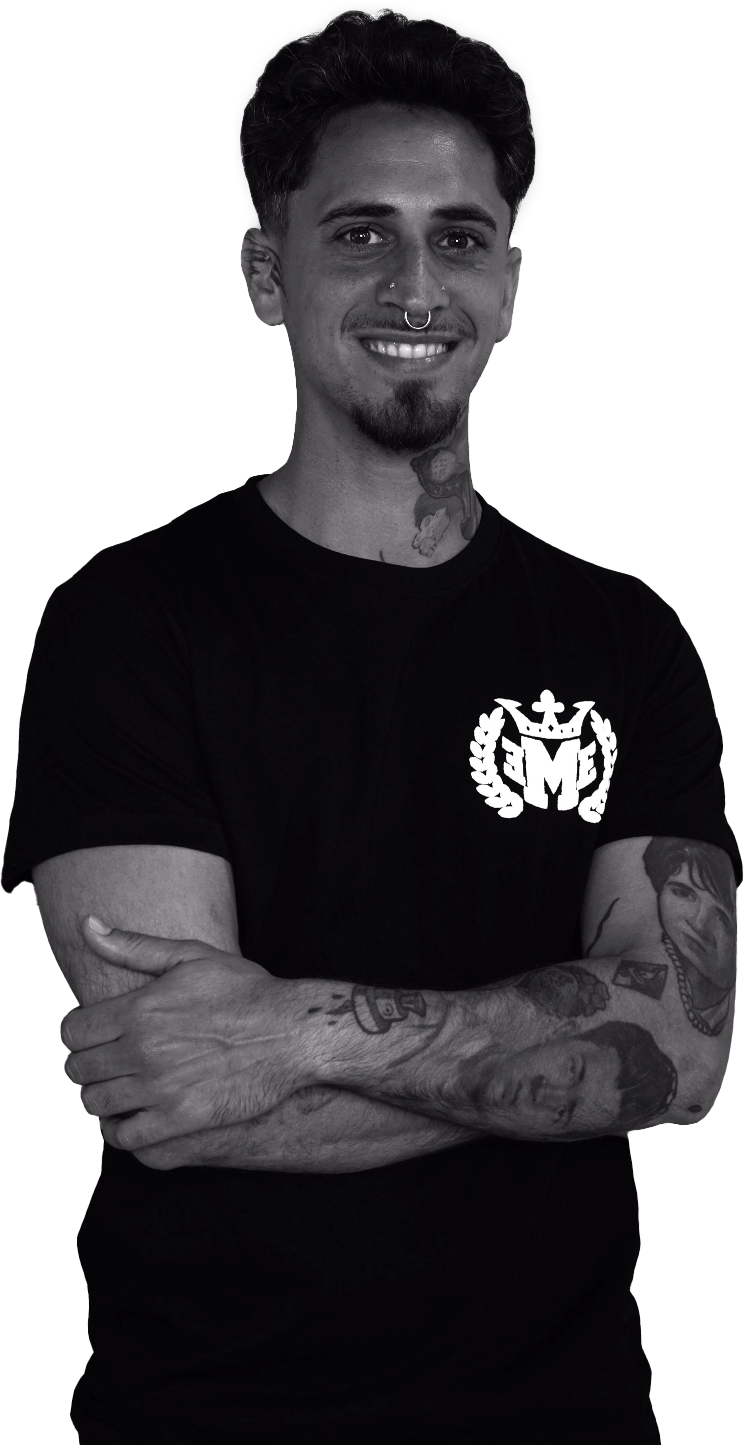 Un hombre con tatuajes en los brazos está de pie con los brazos cruzados en una foto en blanco y negro.
