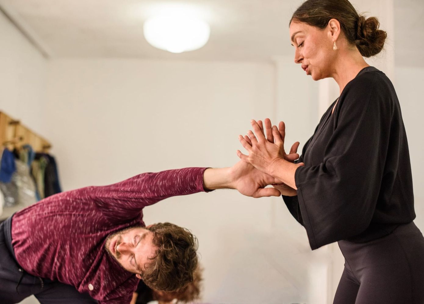 Clase de yoga practicando posturas de equilibrio en un estudio luminoso, con esterillas, bloques