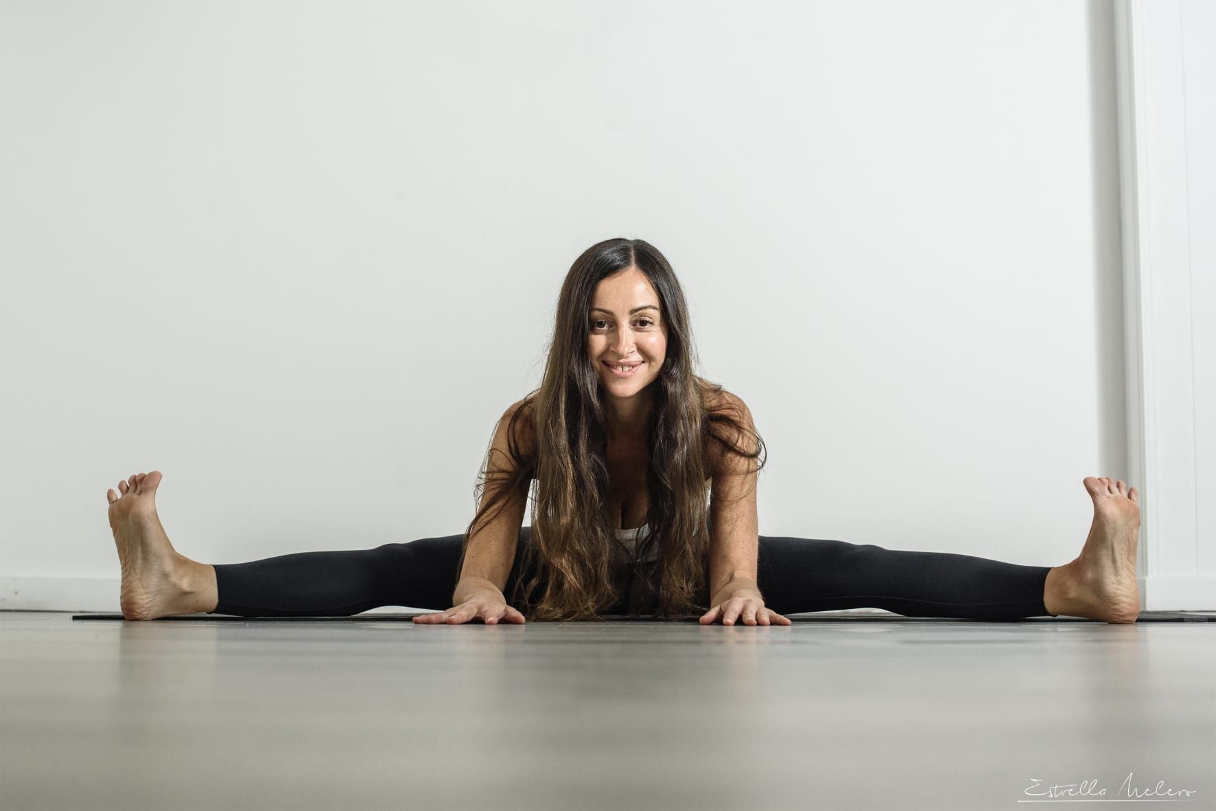 Una persona vestida de negro realiza una postura de arco de yoga contra una pared de piedra