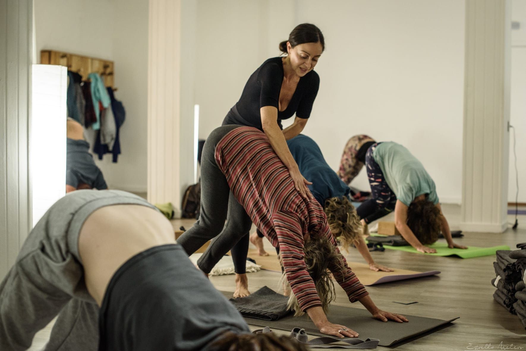 Una persona vestida de negro realiza una postura de arco de yoga contra una pared de piedra