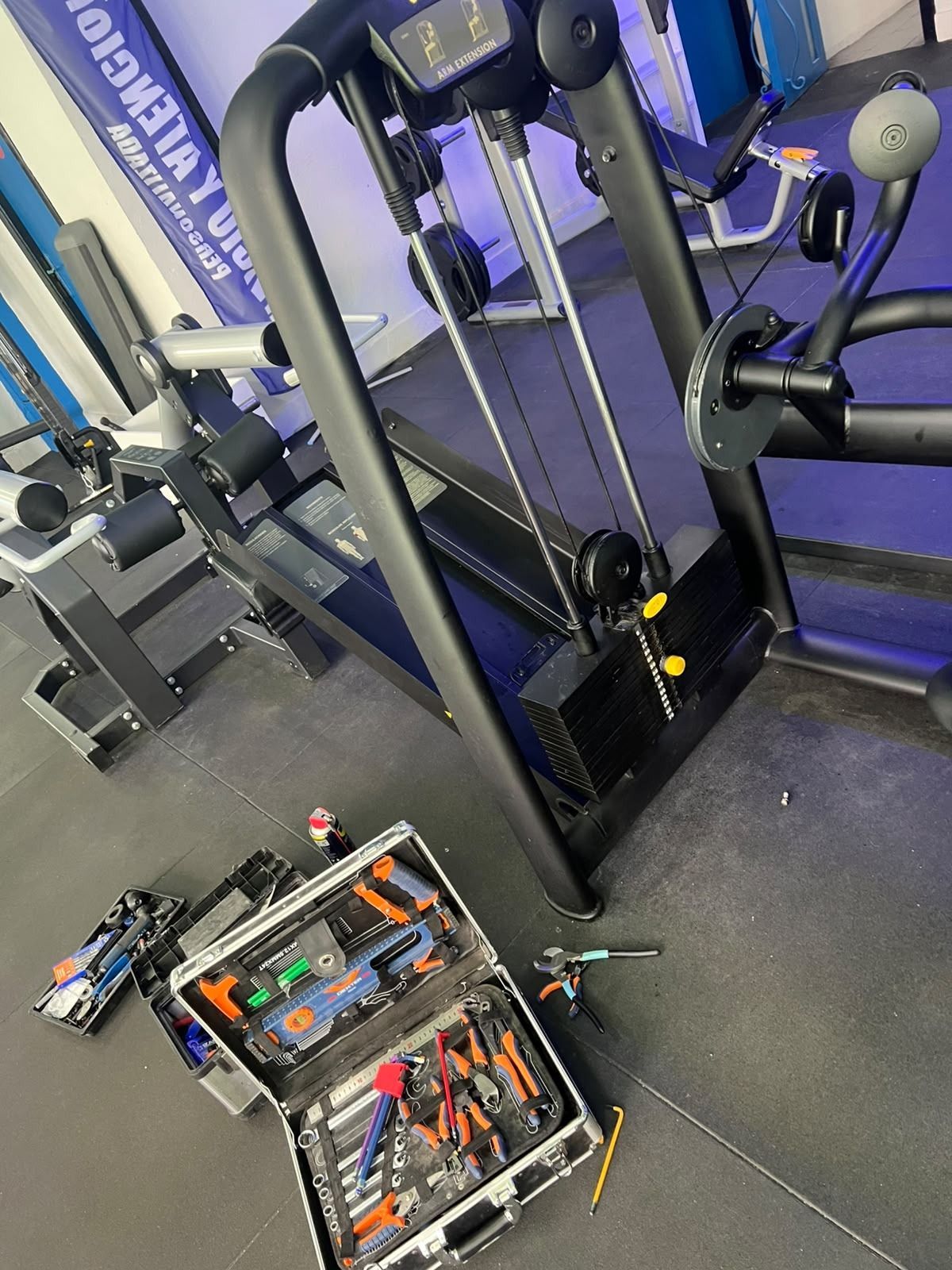 Equipo de gimnasio y una caja de herramientas abierta con varias herramientas en el suelo