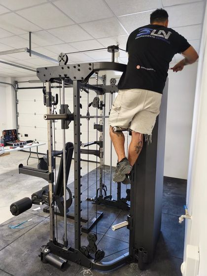 Persona trepando por una máquina de poleas en un gimnasio instalado en un garaje mientras se agarra al marco superior