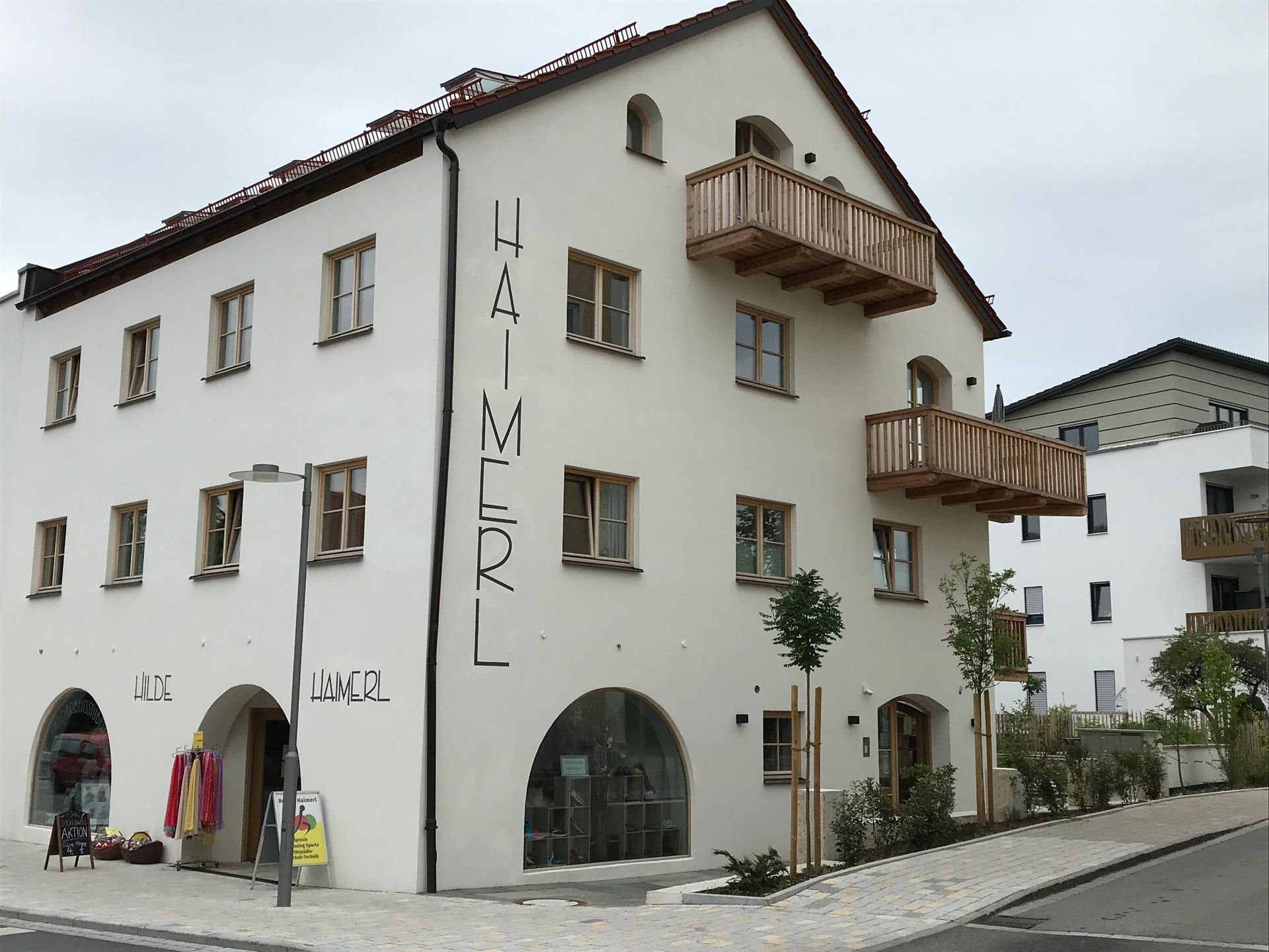 Weißes Gebäude mit „HAIMERL“-Aufschrift, Bogenfenstern und Holzbalkonen.