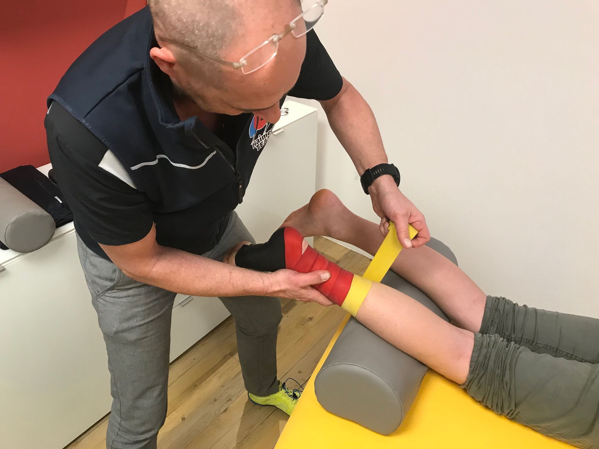 Robert Haimerl führt eine Medical-Flossing-Behandlung durch, Band wird straff um Fuß gewickelt.