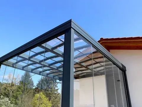 Una pérgola con techo de cristal está situada en el costado de una casa.