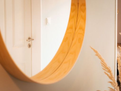 Un espejo redondo con marco de madera está colgado en una pared.