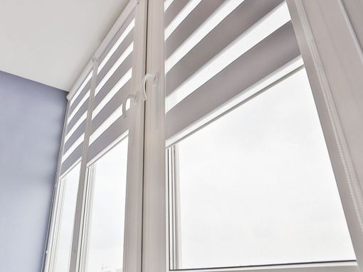 Un primer plano de una ventana con persianas blancas.
