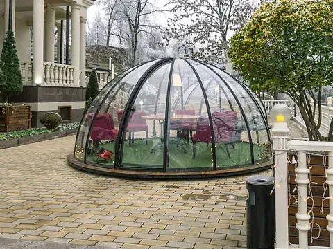 Una estructura en forma de cúpula con mesas y sillas en su interior.
