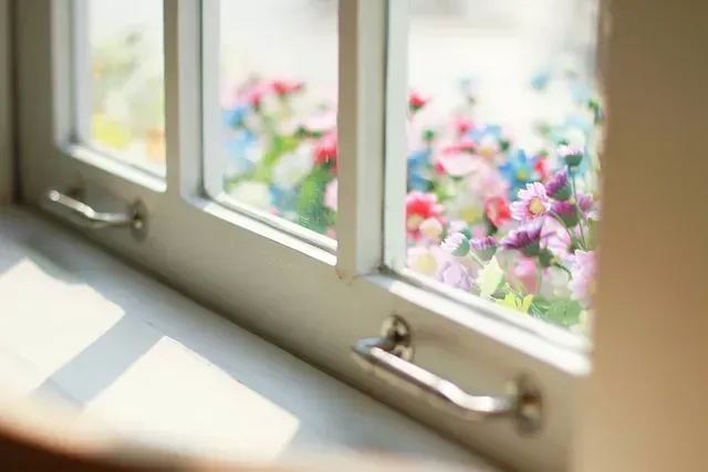 Un primer plano de una ventana con flores saliendo de ella.