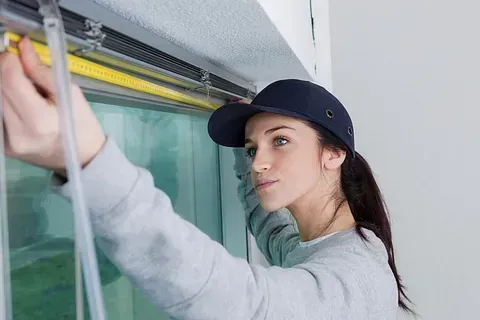 Una mujer está midiendo una ventana con una cinta métrica.