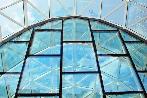 El techo de un edificio con muchas ventanas y un cielo azul reflejado en las ventanas.
