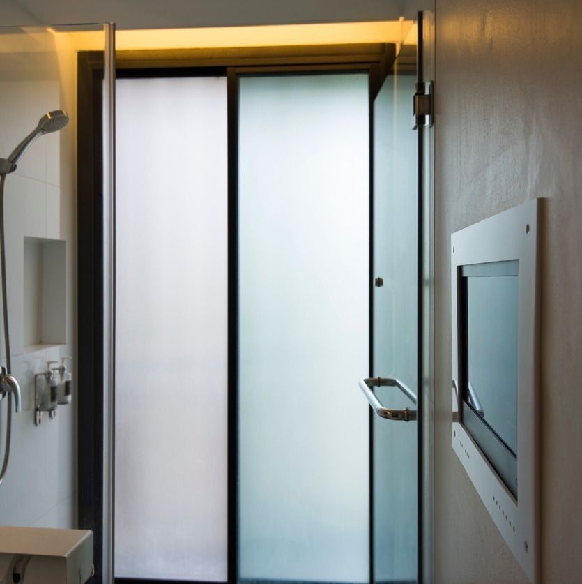 Un baño con puerta corrediza de cristal y un televisor.