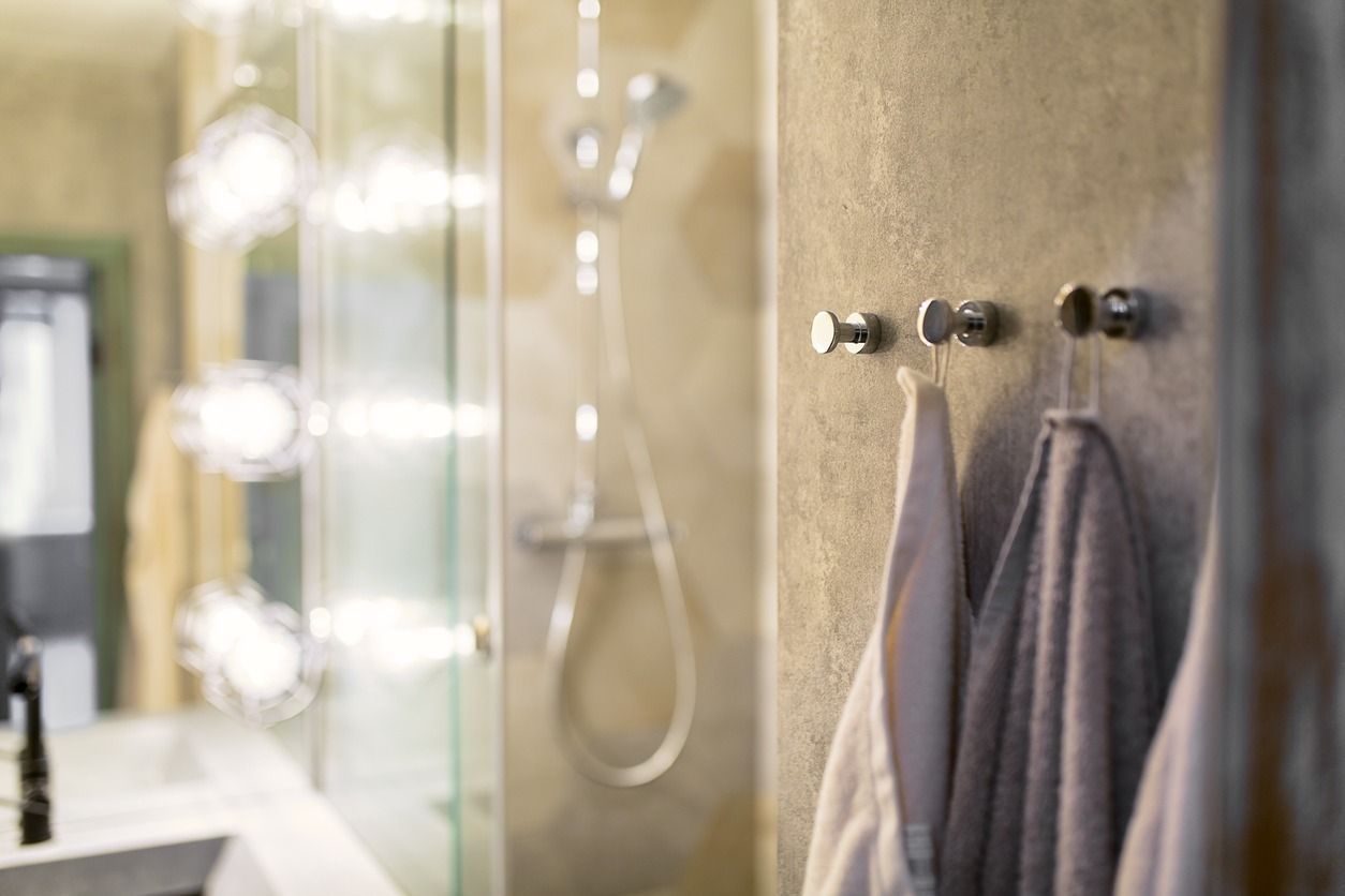 Un baño con toallas colgadas en ganchos y una ducha.