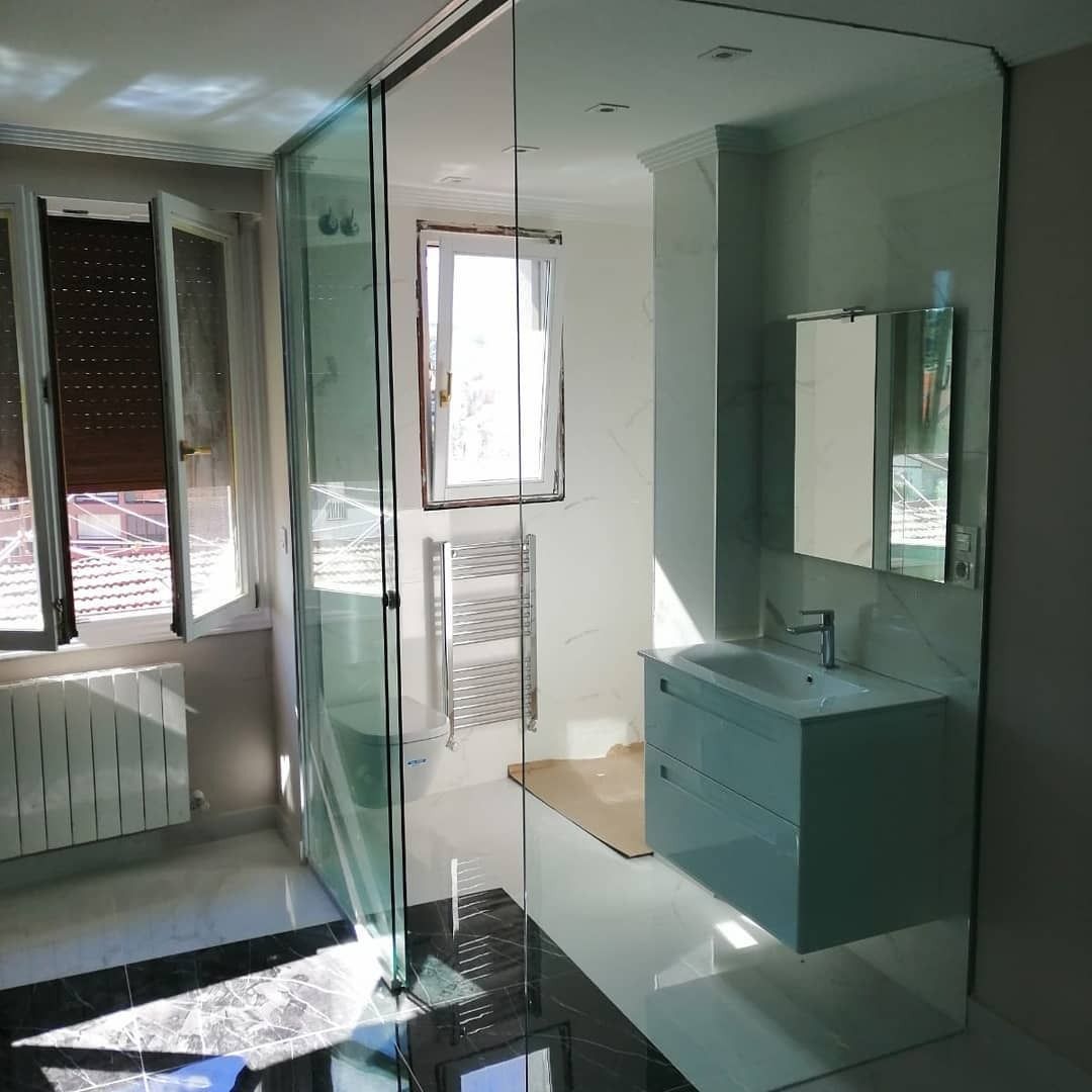 Un baño con lavabo, espejo y puertas corredizas de cristal.