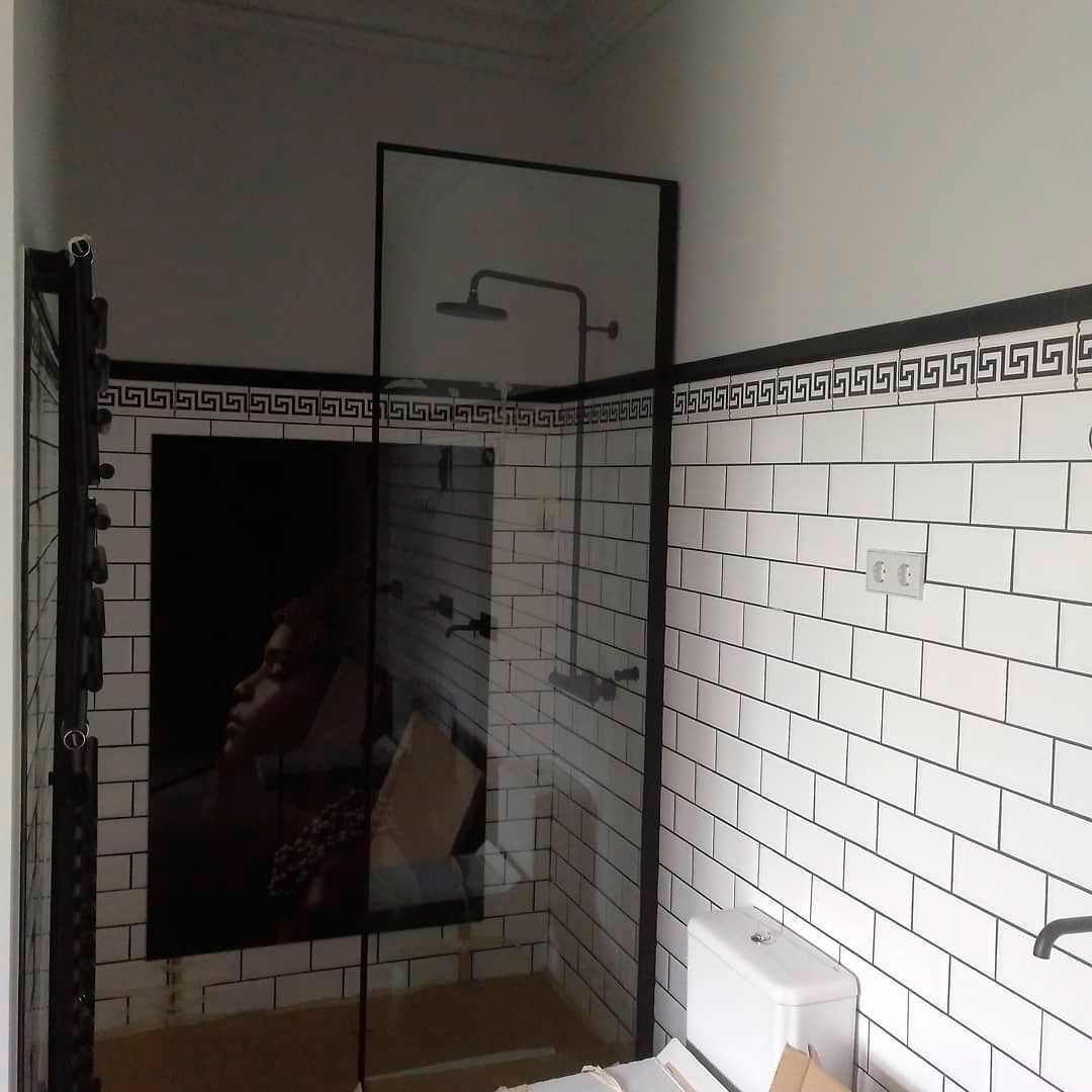 Un baño con ladrillos blancos y una puerta de ducha de cristal.