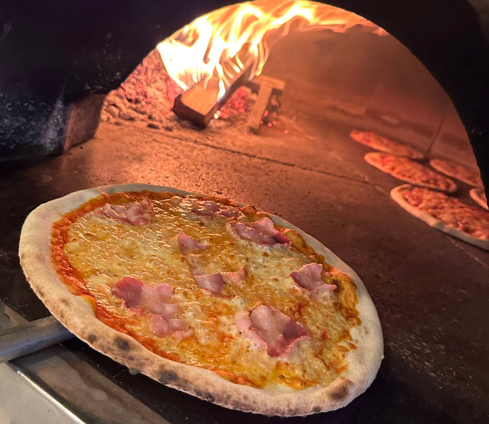 Zwei Personen stossen mit Rotweingläsern bei einem romantischen Abendessen mit Kerzen und Salat an.