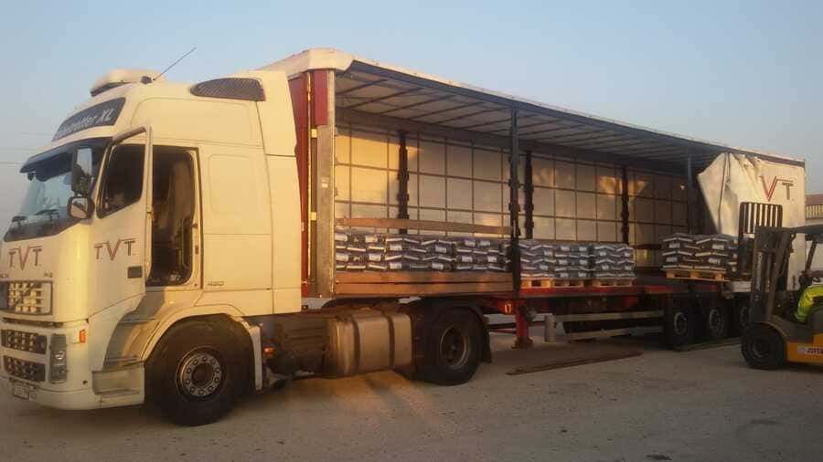 Un camión semirremolque blanco está estacionado en un estacionamiento al lado de una carretilla elevadora.