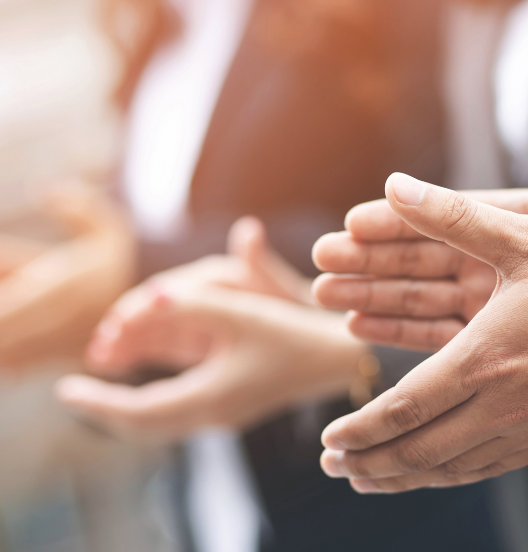 Des mains qui applaudissent dans un contexte professionnel, avec un flou artistique sur les mains.