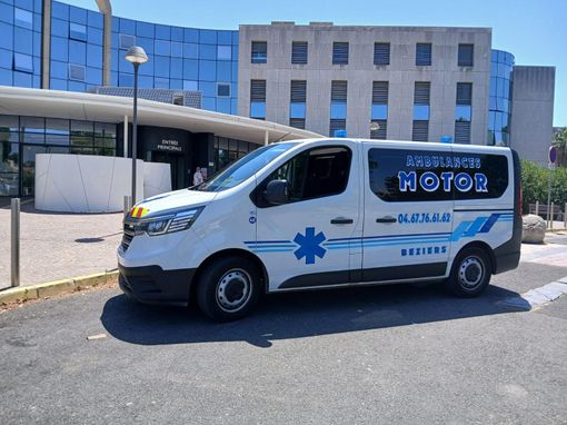 Ambulance blanche garée devant un bâtiment hospitalier par une journée ensoleillée