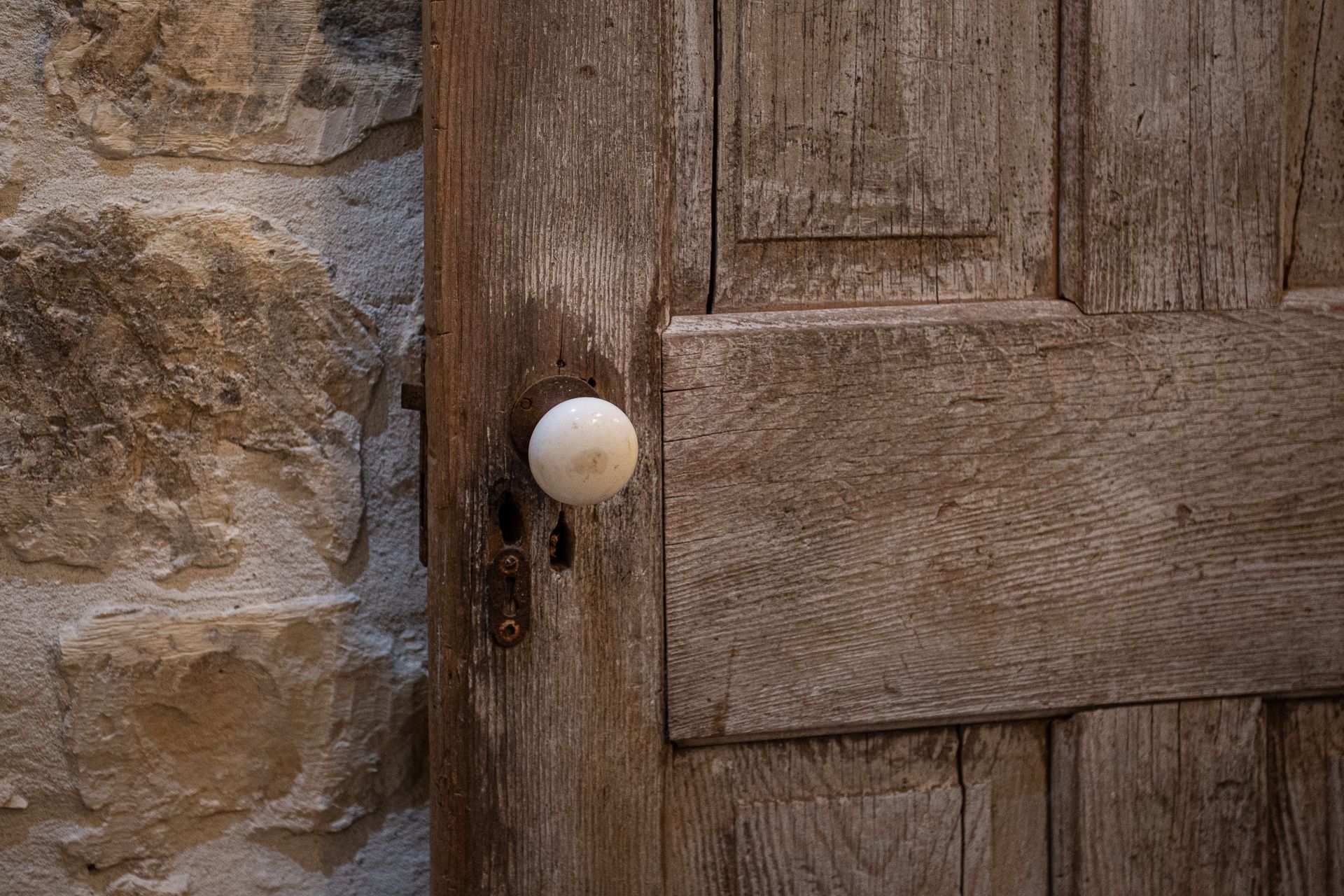 A wooden door with a white knob is against a stone wall.