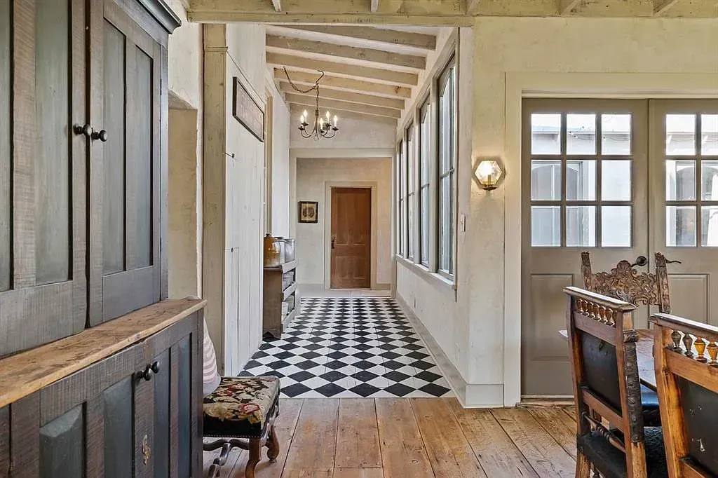 A long hallway leading to a dining room with a black and white checkered floor.