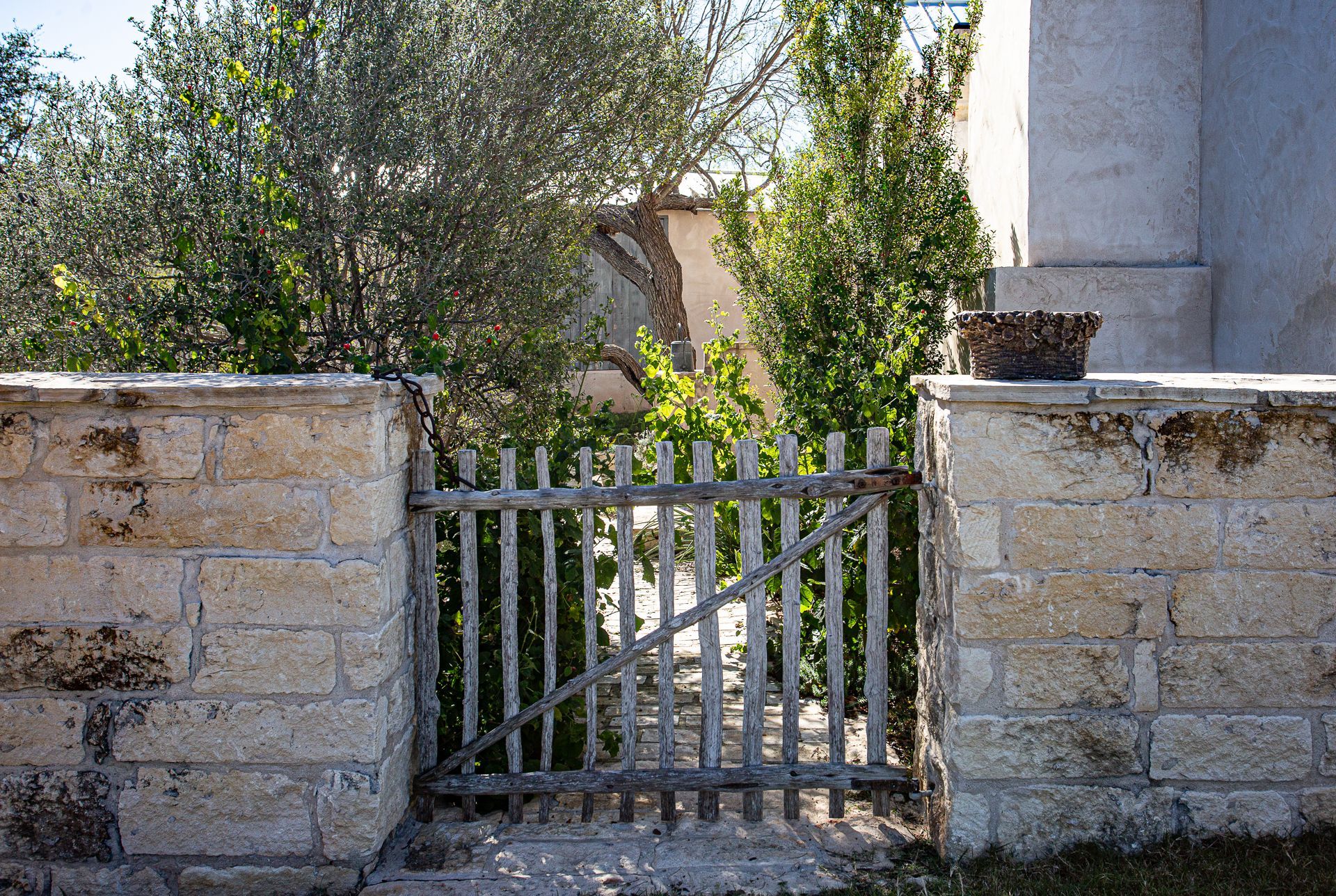 A stone wall with a metal gate leading to a garden.