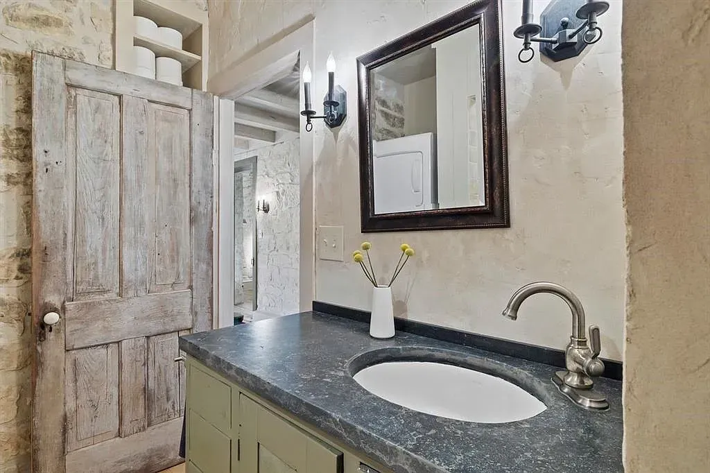 A bathroom with a sink , mirror , and cabinets.