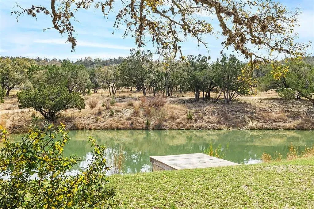 A large body of water surrounded by trees and grass with a dock in the foreground.