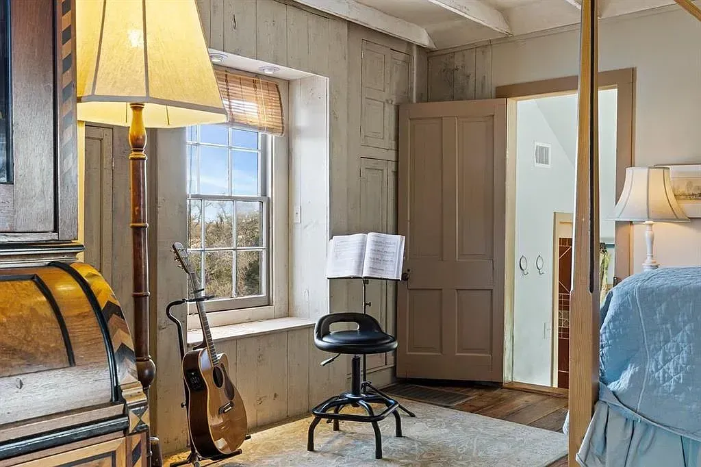 A bedroom with a canopy bed , a lamp , a violin , and a music stand.
