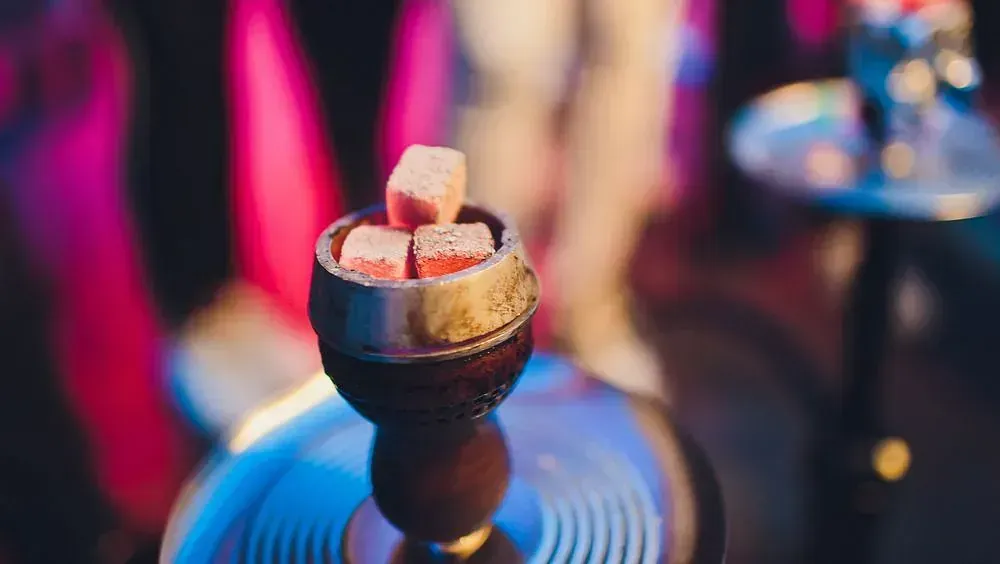 Una pipa de agua con terrones de azúcar dentro está sobre una mesa.