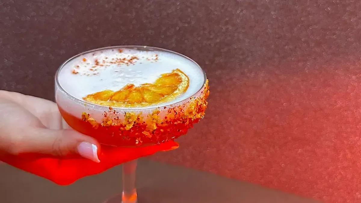Una mujer sostiene una copa de martini con una rodaja de naranja encima.