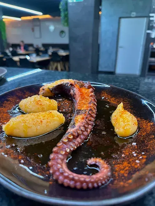 Un primer plano de un plato de comida con un pulpo encima.