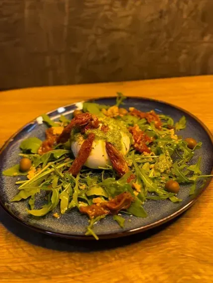 Un plato azul cubierto con ensalada sobre una mesa de madera.