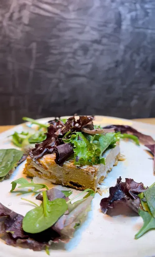 Un plato blanco cubierto con un trozo de carne y lechuga.