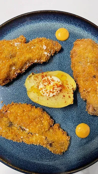 Un plato azul cubierto con comida frita y patatas.