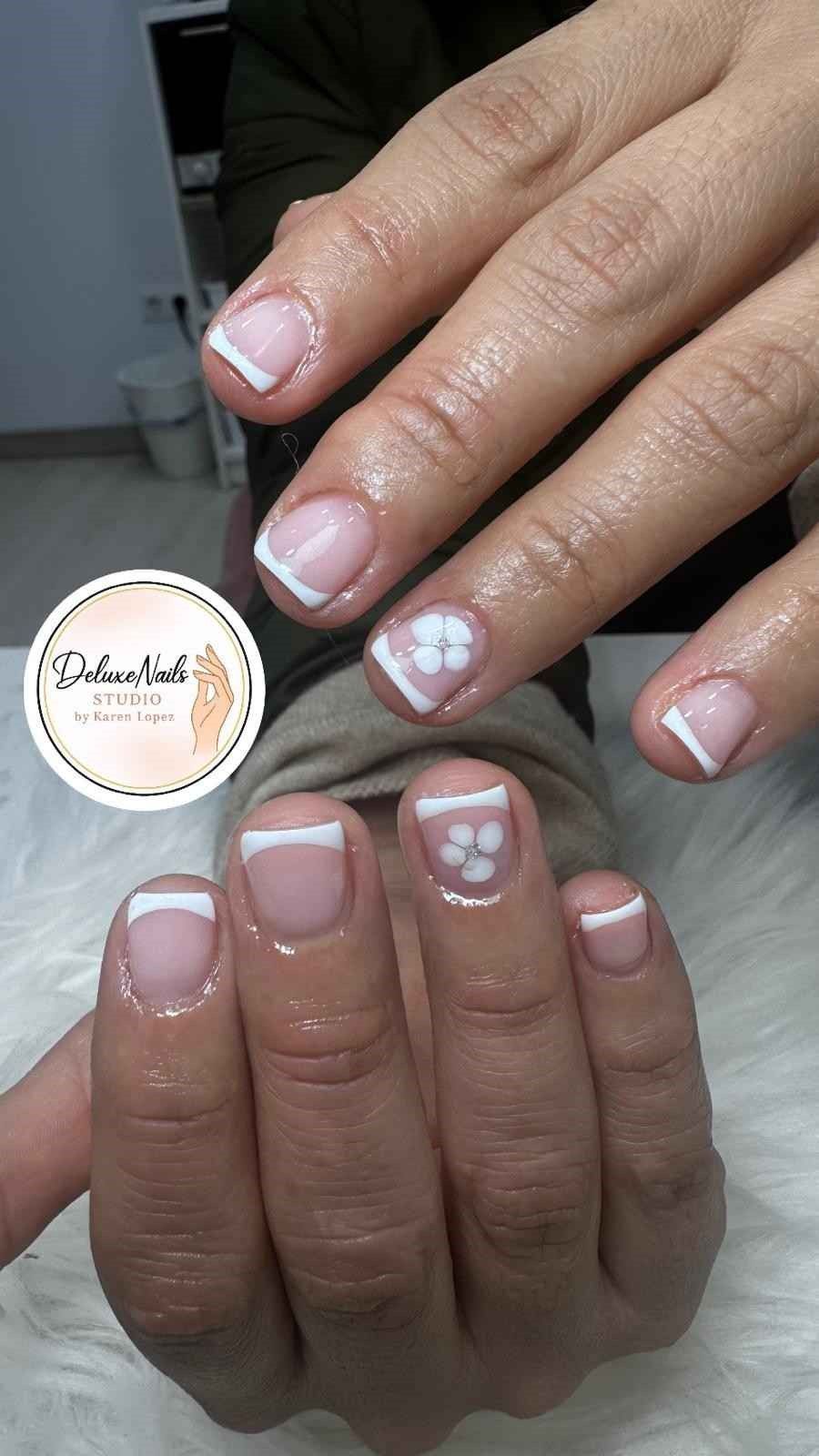 Manos que muestran manicura francesa con esmalte rosa pálido y detalles de corazones blancos en los dedos anulares.