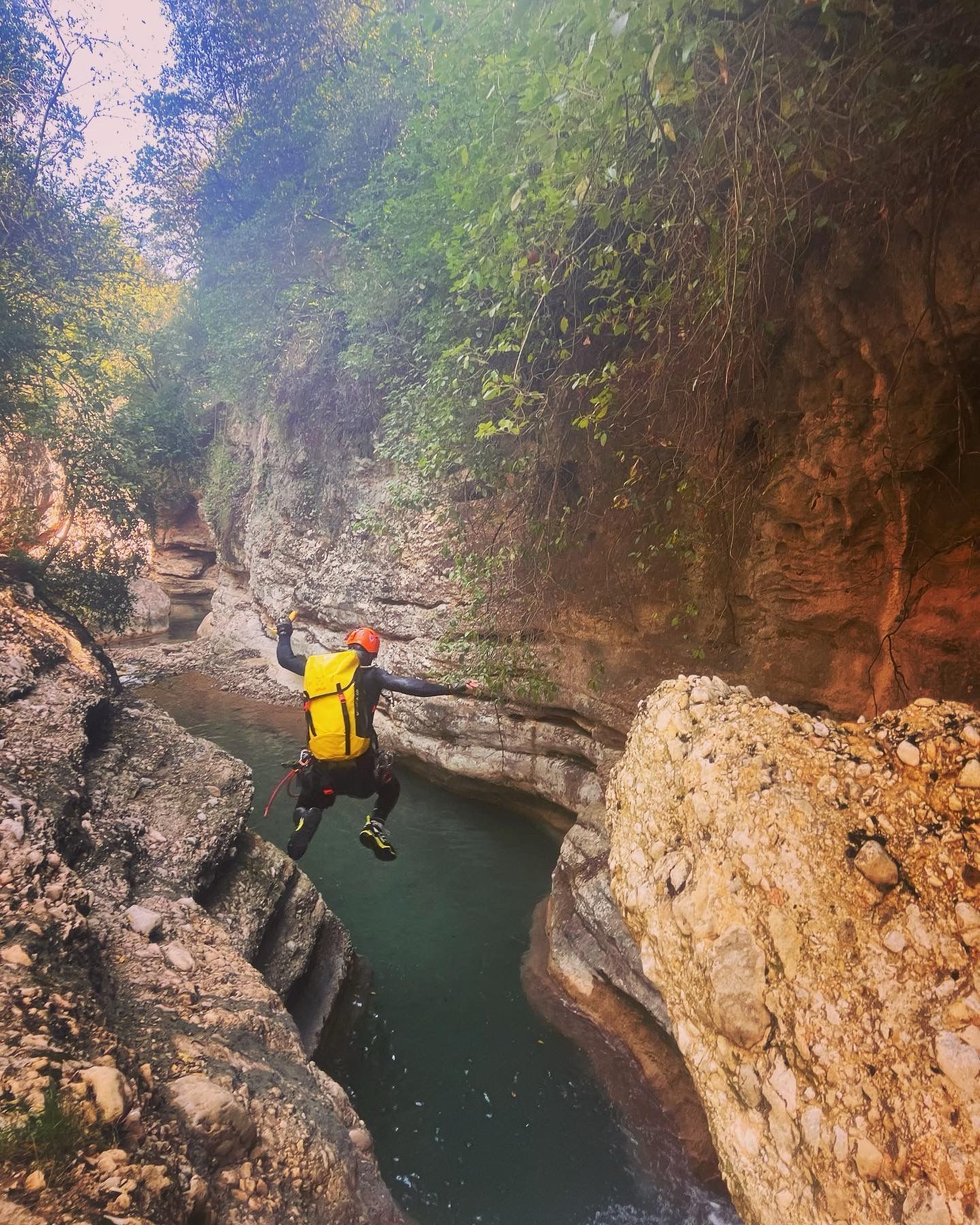 Una persona con una mochila se lanza a un río.