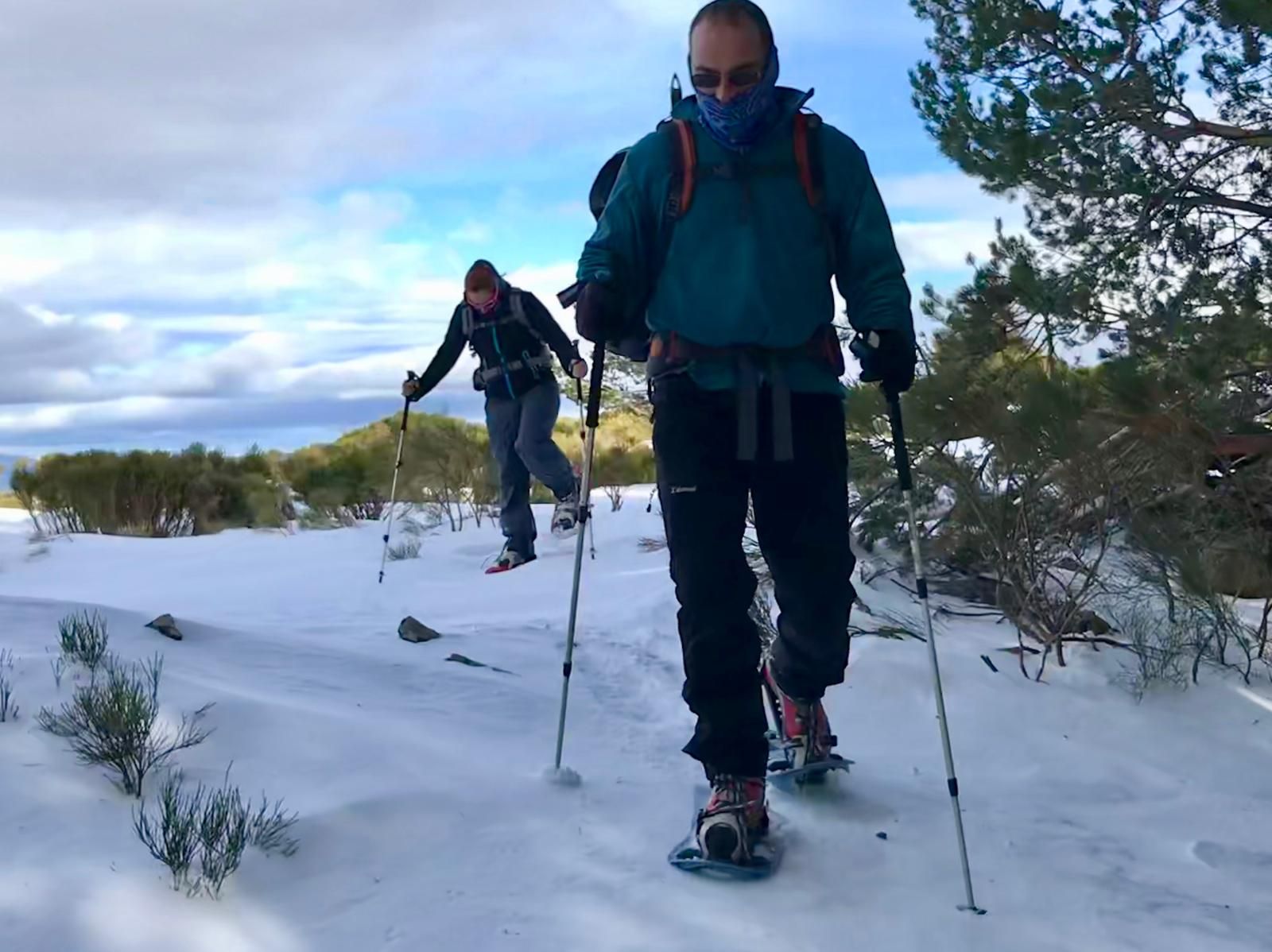 Un grupo de personas camina con raquetas de nieve en la nieve.