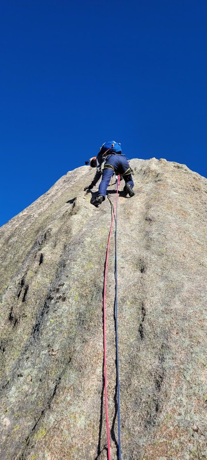 Una persona está trepando por la ladera de una gran roca.