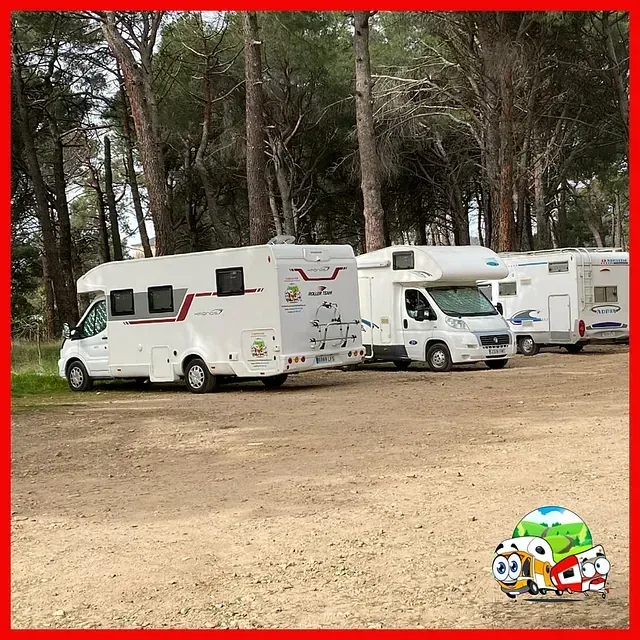 Una fila de autocaravanas están estacionadas en un terreno de tierra.