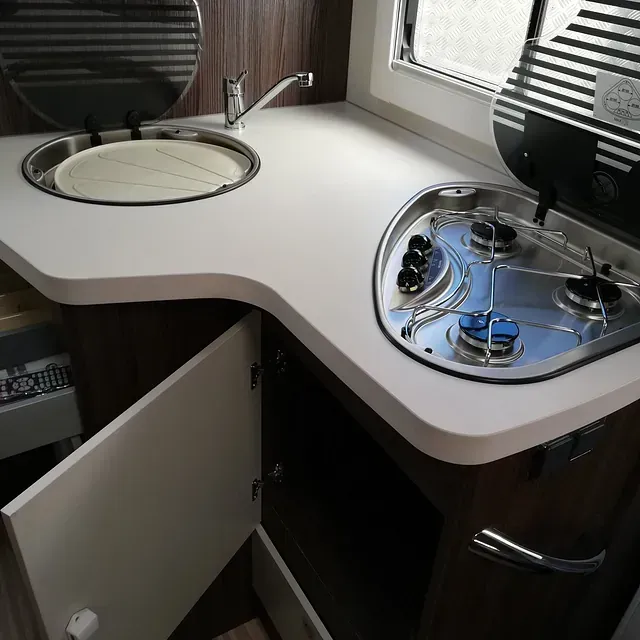 Una cocina con fregadero y estufa con la puerta abierta.