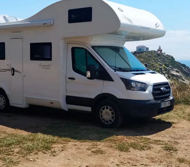 Una autocaravana blanca está estacionada en la cima de una colina de tierra.