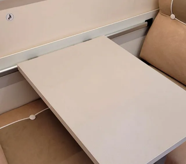Una mesa blanca está encima de un sofá marrón.