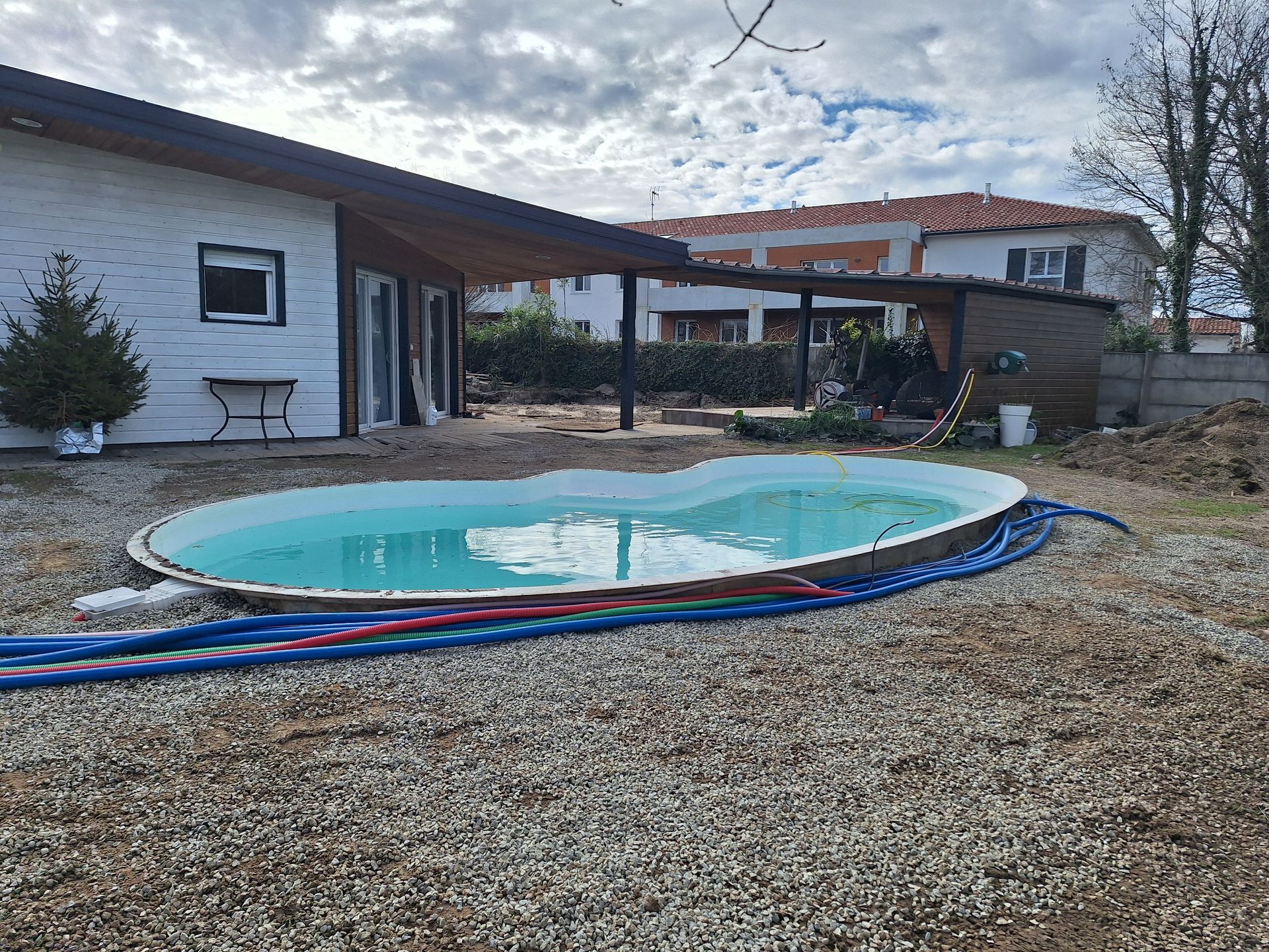 Une piscine en construcion en forme organique avec gravier autour