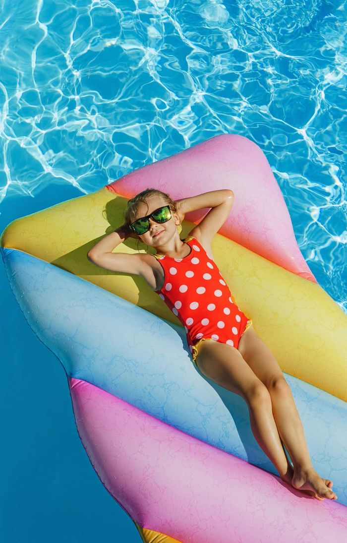 Une enfant allongée sur un matelas gonflable dans une piscine