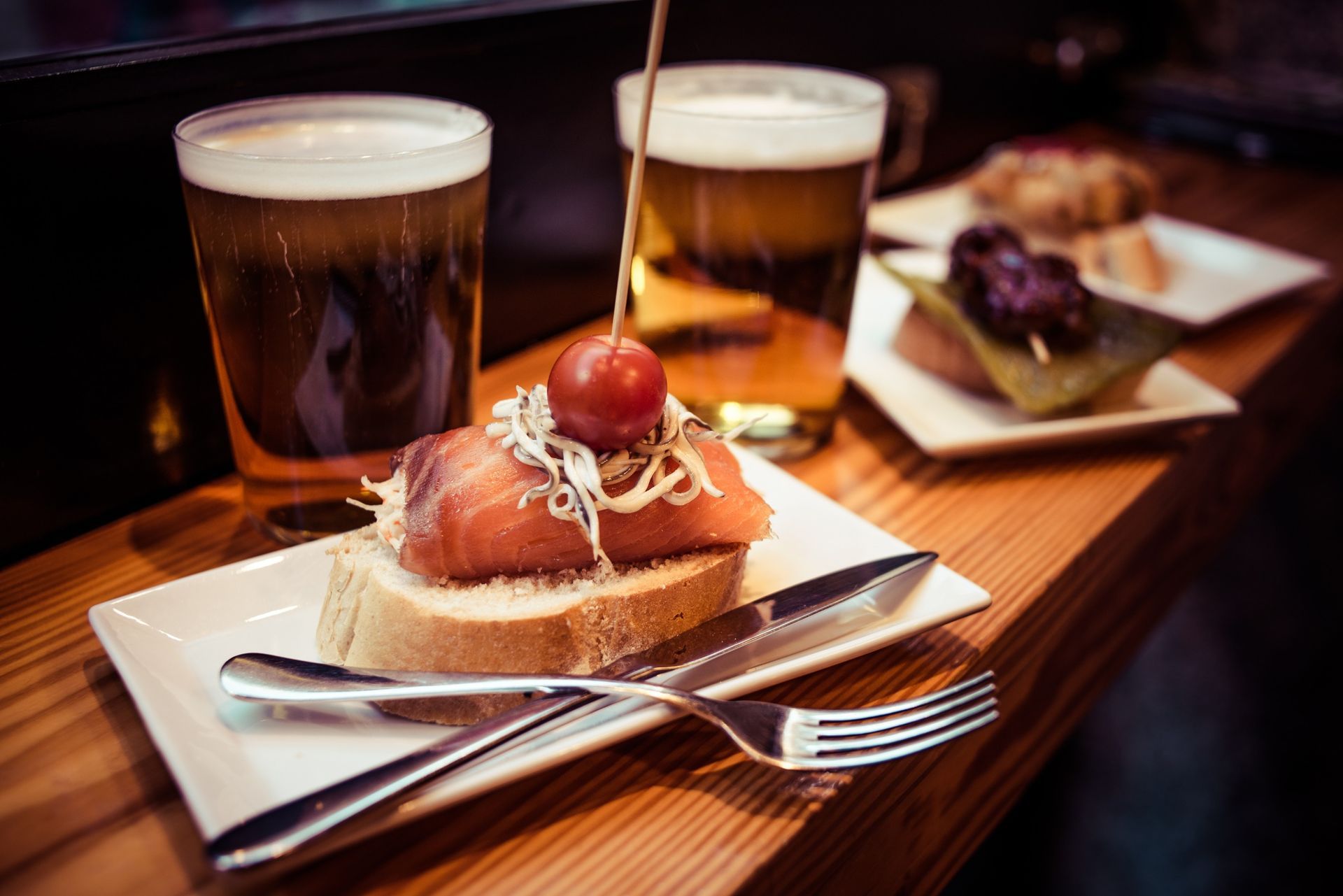 Un plato de comida y dos vasos de cerveza en una mesa de madera.