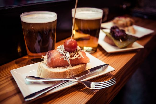 Un plato de comida y dos vasos de cerveza en una mesa de madera.