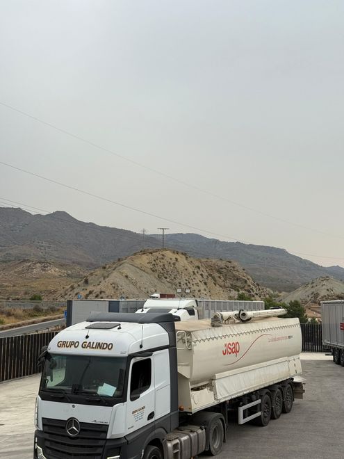 Camión cisterna estacionado cerca de las colinas en un día nublado.