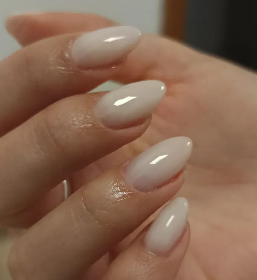 Mano con manicura blanca brillante en forma de almendra