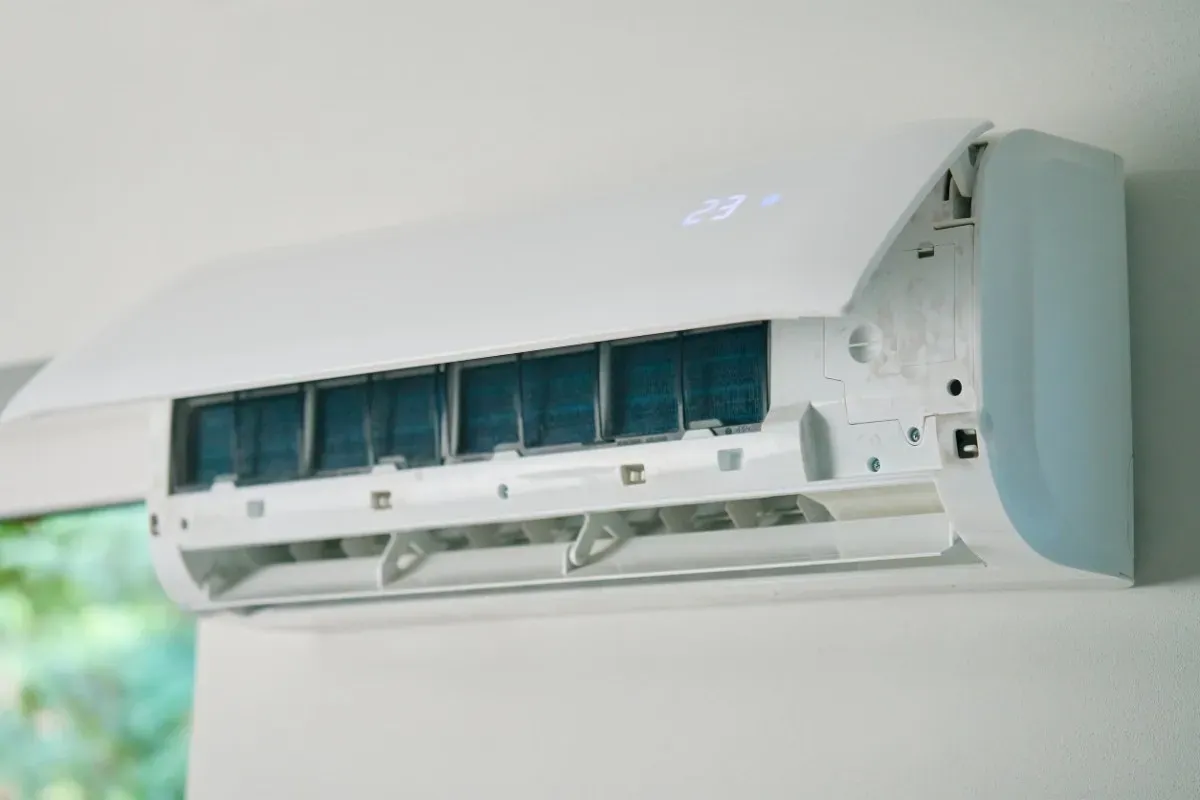 Unidad de aire acondicionado de pared de color blanco, con rejillas de ventilación abiertas y aletas de refrigeración visibles.